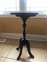 Front view of the antique wooden side table showing the round top, turned spindle column, and tripod base.