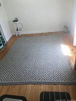 Full view of the large gray and white chevron patterned area rug laid on hardwood floor, showing overall size and condition.