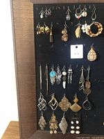 Black velvet display with multiple pairs of costume jewelry earrings in varied styles and materials.