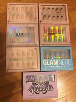 10 sets of Glamnetic reusable press-on nails in original packaging, various nude and holographic styles visible