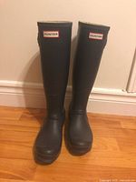 Front view of the navy blue Hunter rain boots, showing the logo and overall shape.