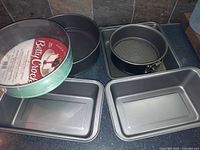 Photo of assortment of metal baking pans showing round cake pans, rectangular loaf pans, and square cake pan.