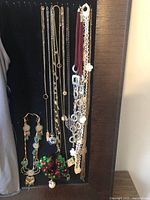 Wide view showing the majority of necklaces and earrings hanging on a black background