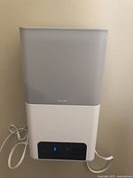 Front facing view of the Petcube pet camera and treat dispenser device with power cable visible.