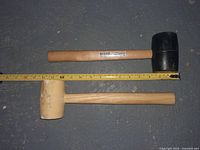 Two rubber mallets placed side by side on a floor with a measuring tape underneath for scale.