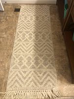 Full length view of beige southwestern flatweave area rug runner with geometric pattern and fringed edge.