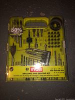 Ryobi green plastic case with drill and driving bits neatly organized inside, front view with label showing 60-piece kit.