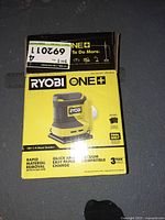 Box of Ryobi 18V One+ 1/4 Sheet Sander showing branding, model info and features like rapid material removal, quick paper change, vacuum compatible.