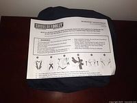 Photo of Shoulder Dolly instruction manual placed on top of folded black moving straps, showing usage warnings and instructions for putting the straps on correctly.