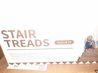 Box showing label 'STAIR TREADS' with pack of 15 indicated, and product details including indoor use, self-adhesive, recommended for homes with kids and pets.
