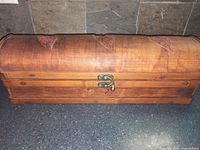 Side view of tea bag holder showing wooden body with curvature, clasp lock, and leaf appliques on lid.