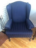 Front view of Victorian style armchair with dark blue striped upholstery and one arm cover on the right armrest.