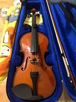 Full size 4/4 violin inside blue velvet-lined case showing violin front and bow.