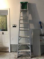 Full view of the Werner aluminium ladder showing 7 steps and green top platform in a garage setting.