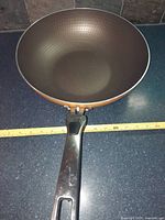 Top view of the wok pan showing the textured interior surface and attached black handle lying on a dark countertop.