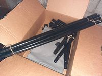 Metal frame parts and gray mesh fabric inside an open cardboard box for the XL dog cot, showing disassembled pieces.