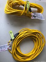 Photo showing two coiled yellow electrical cords each 40 feet long, with plugs and tags visible.