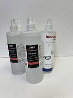 Close-up of three spray bottles, two Fog-A-Way and one Honeywell UVEX Clear, showing labels and nozzle tops