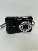 Front view of black Fujifilm digital camera showing lens and 10.2 MP marking