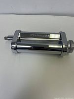 Front angled view of KitchenAid pasta roller attachment showing chrome finish and thickness adjustment dial.