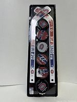 Front view of two mini hockey sticks and five mini pucks in packaging showing player names and logos