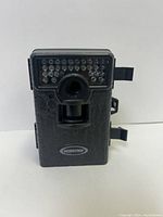 Front view of MOULTRIE mini trail camera showing infrared LED array above central lens and textured black body