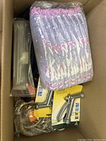 Box with garden hose nozzles still in Blaster packaging, black coiled hose, rope, and folded towels