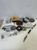 Mixed lot of items including battery pack, sanding discs, wire spool, and rope.