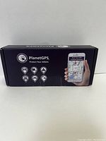 Front and side of boxed PlanetGPS real-time GPS tracker showing product branding and app interface image.