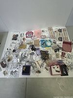 Wide view of all costume jewelry and accessory items spread out on white surface showing various packaged and unpackaged pieces