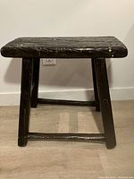 Front view of the ebonized wooden step stool showing the top with visible wood grain and signs of wear.