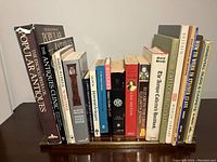 Photo showing 17 books on antiques and history topics standing on a wooden Victorian rack.