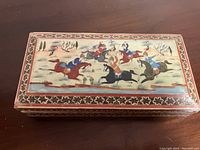 Top view of rectangular Persian-style decorative wooden box with painted horse riders and ornate borders.
