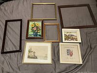 Top view of all 7 frames and artworks laid out on bed showing the variety of artwork and frame styles.