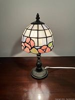 Front view of Tiffany style stained glass lamp illuminating on a wooden surface.