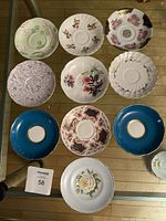 Top view of 10 assorted vintage bone china tea cup saucers showing different floral and decorative patterns in various colors.