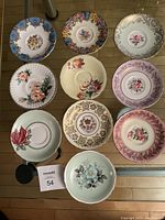 Top view of all 10 assorted vintage bone china tea cup saucers arranged in two rows on glass surface