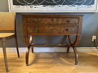Front view of nightstand showing two drawers, burl veneer fronts, brass knob pulls, curved crossed-leg base.