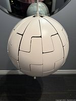 Closed spherical view of the white panelled IKEA ceiling lamp suspended from its cord.