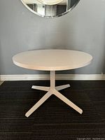 Front view of the white Knoll round table showing full tabletop and base on dark carpet.
