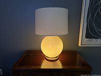 Lamp illuminated on base light only, showing warm glow from ceramic base.