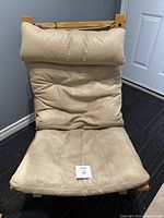 Front view showing cream leather cushioned seat and large padded headrest on wooden frame.