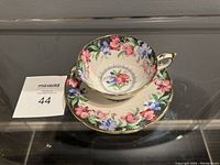 Tea cup and saucer placed on a reflective surface with MaxSold number card beside.