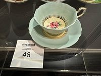 Photo of the tea cup showing the interior rose design and saucer beneath