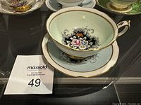 Photo showing the tea cup inside the saucer with detailed floral pattern and gold trim.