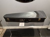 Closed black hard case with handle and two metal latches. Exterior shows light surface wear.