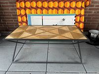 Top view photo of rectangular coffee table showing geometric pattern on wooden top and metal edge frame.