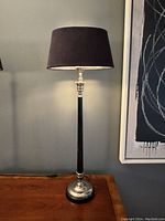 Single vintage tuxedo table lamp on wooden surface against a gray wall.