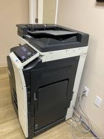 Left side angle of Konica Minolta bizhub C224e showing paper trays and side panel