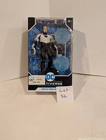 Front view of DC Multiverse Shriek Unmasked figure in original packaging with two blue circular accessories included.